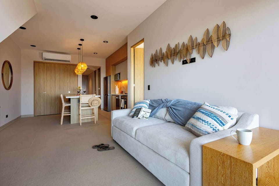 Bright living area w/ sofa seating, TV & warm lighting flowing into the dining space