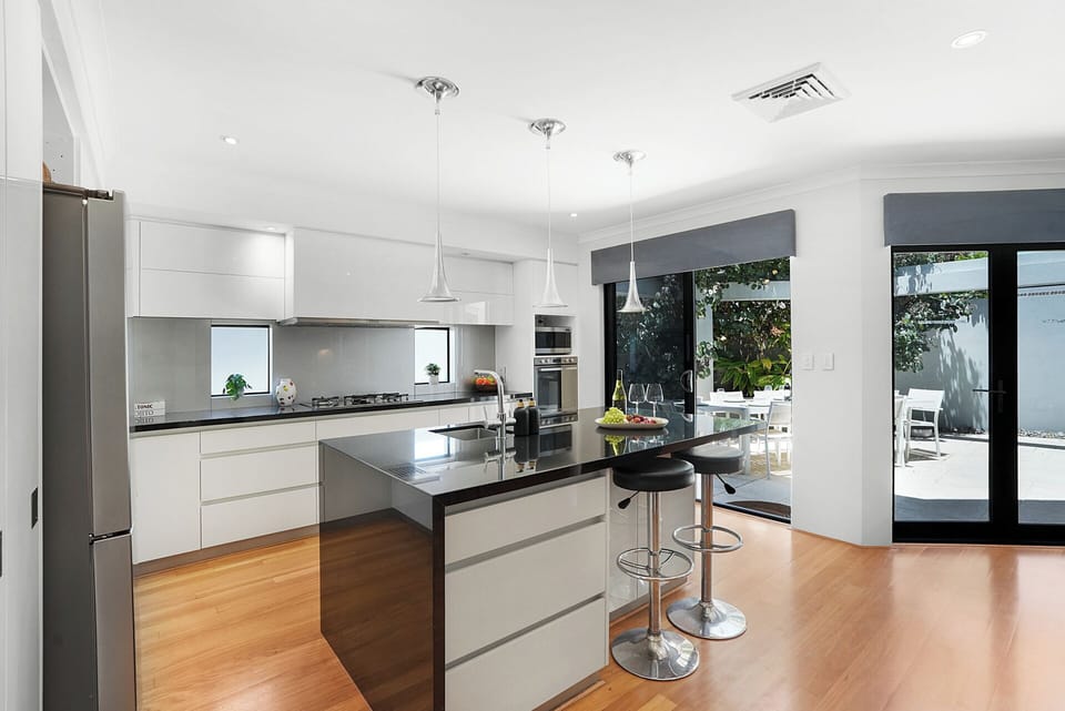 Sleek, fully equipped kitchen with stone island bench and modern pendant lighting.