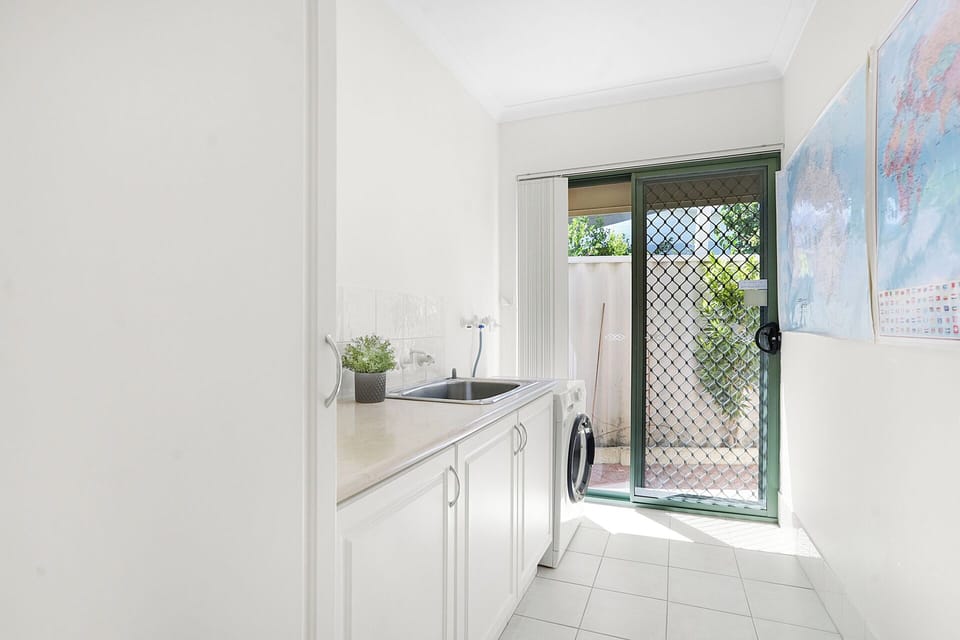 Bright laundry with washer, sink, and direct outdoor access for easy convenience.