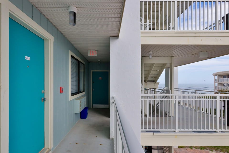 Bright, airy hallway with vibrant turquoise doors and ocean views