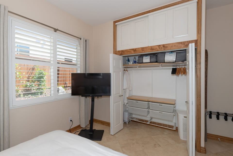 Open closet with hanging space, storage, and nearby TV