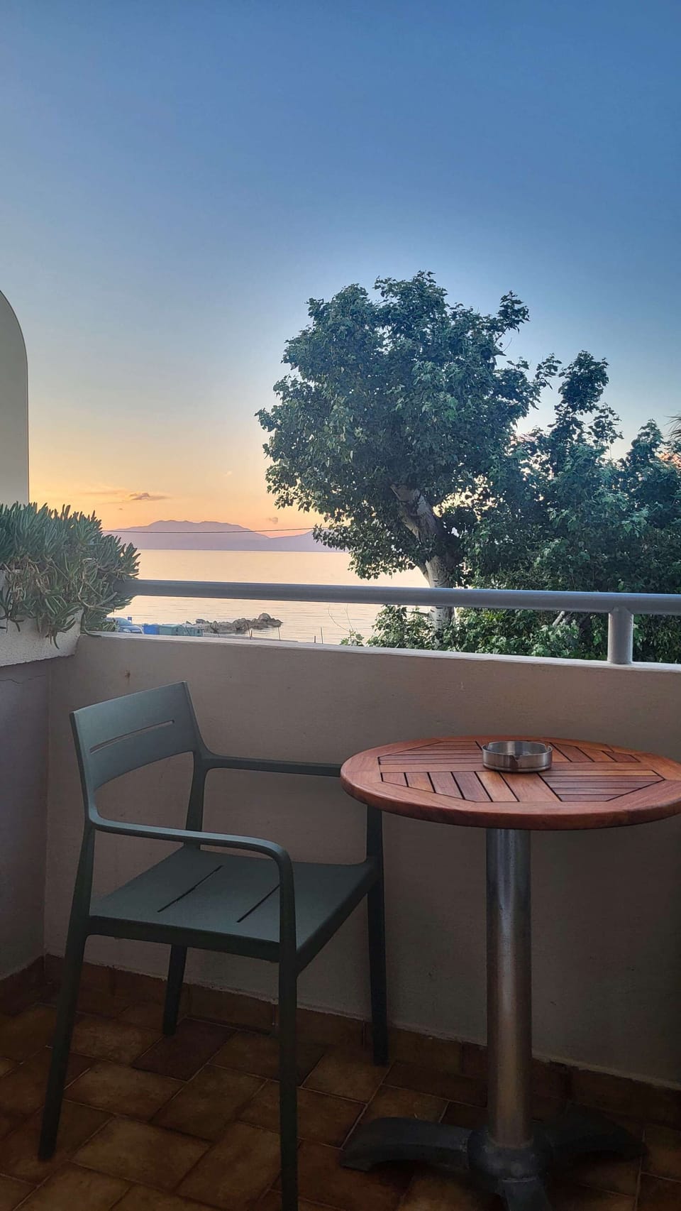 The balcony table and chairs at dusk, with the Gulf of Corinth settling into its evening calm below — a view that changes character through the day but is always worth sitting with.