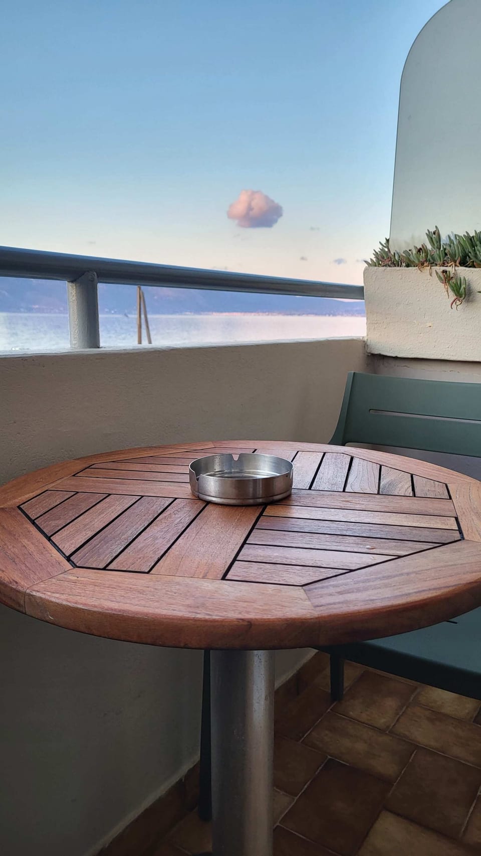 The balcony table and chairs with the Gulf of Corinth spread out directly in front — this is where most mornings will start and most evenings will end, with a view that earns the studio its place on the waterfront.
