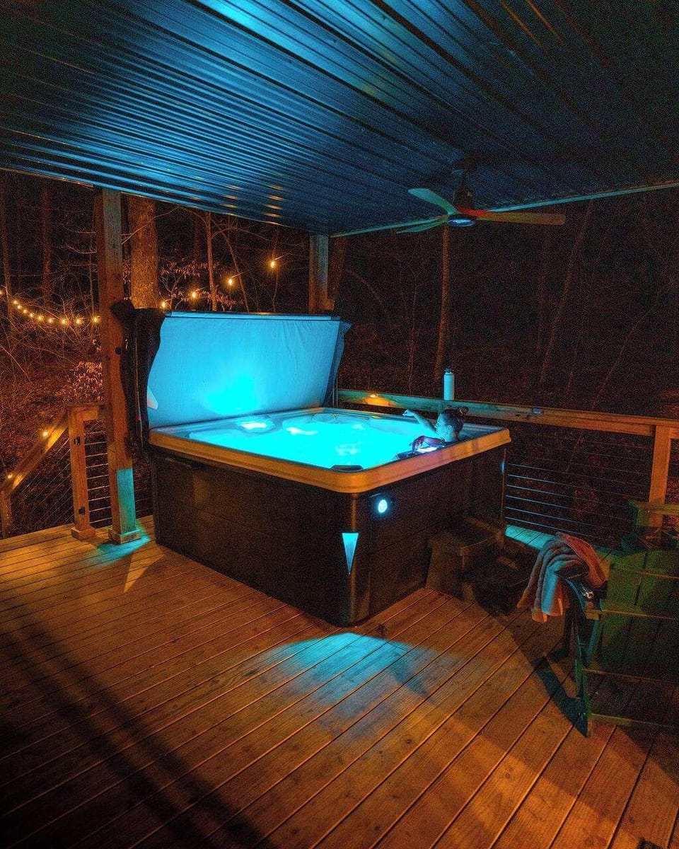 Hot Tub Retreat: Dive into relaxation beneath twinkling lights and serene forest views!
