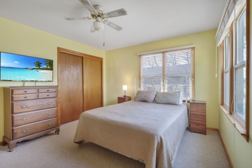 Drift off to sleep in your cozy bedroom with soft linens, tropical artwork, and gentle ceiling fan breeze.