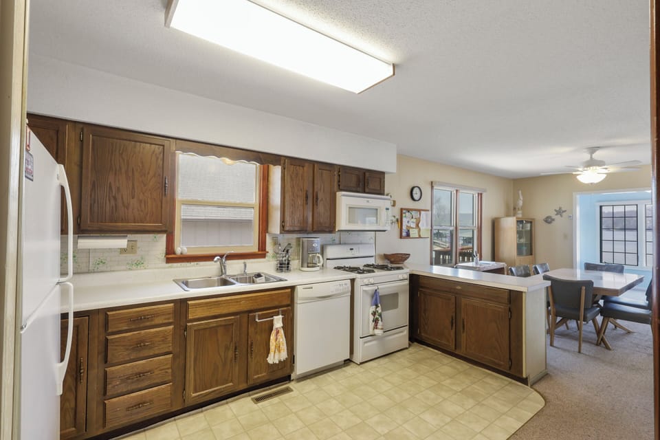 Your fully equipped kitchen awaits with everything needed to prepare meals, featuring rich wood cabinets and convenient breakfast bar seating.