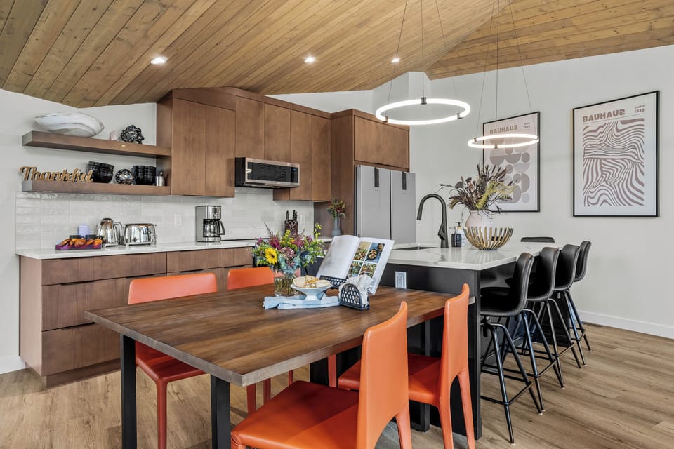 Warm wood finishes with open shelving and a long dining table.