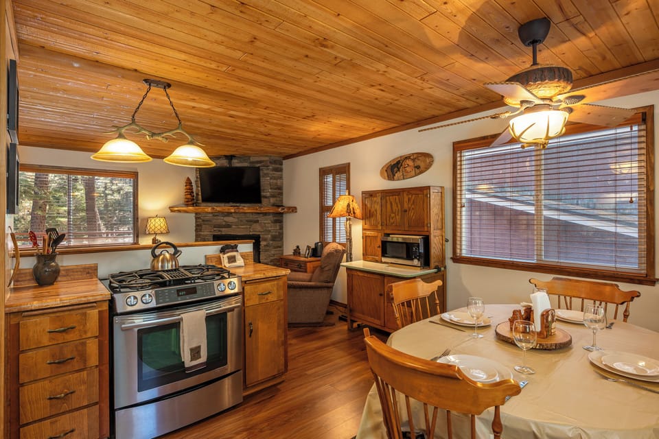 Cozy up in your rustic cabin retreat where wood-paneled ceilings and a stone fireplace create warmth, while a fully equipped kitchen invites you to prepare meals surrounded by charming, mountain-inspired touches.