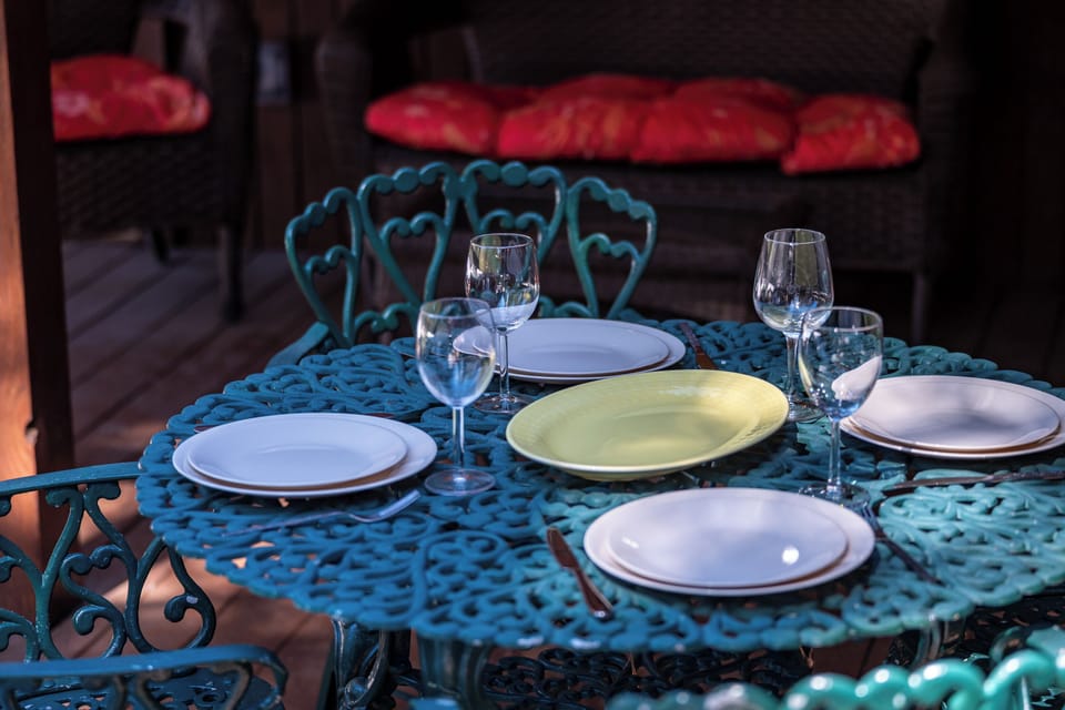 Your romantic dinner awaits at this charming turquoise table, complete with elegant place settings and wine glasses for intimate evenings.