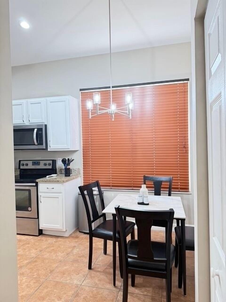 Your bright, modern kitchen-dining space features sleek white cabinetry, stainless steel appliances, and warm wood blinds for privacy.