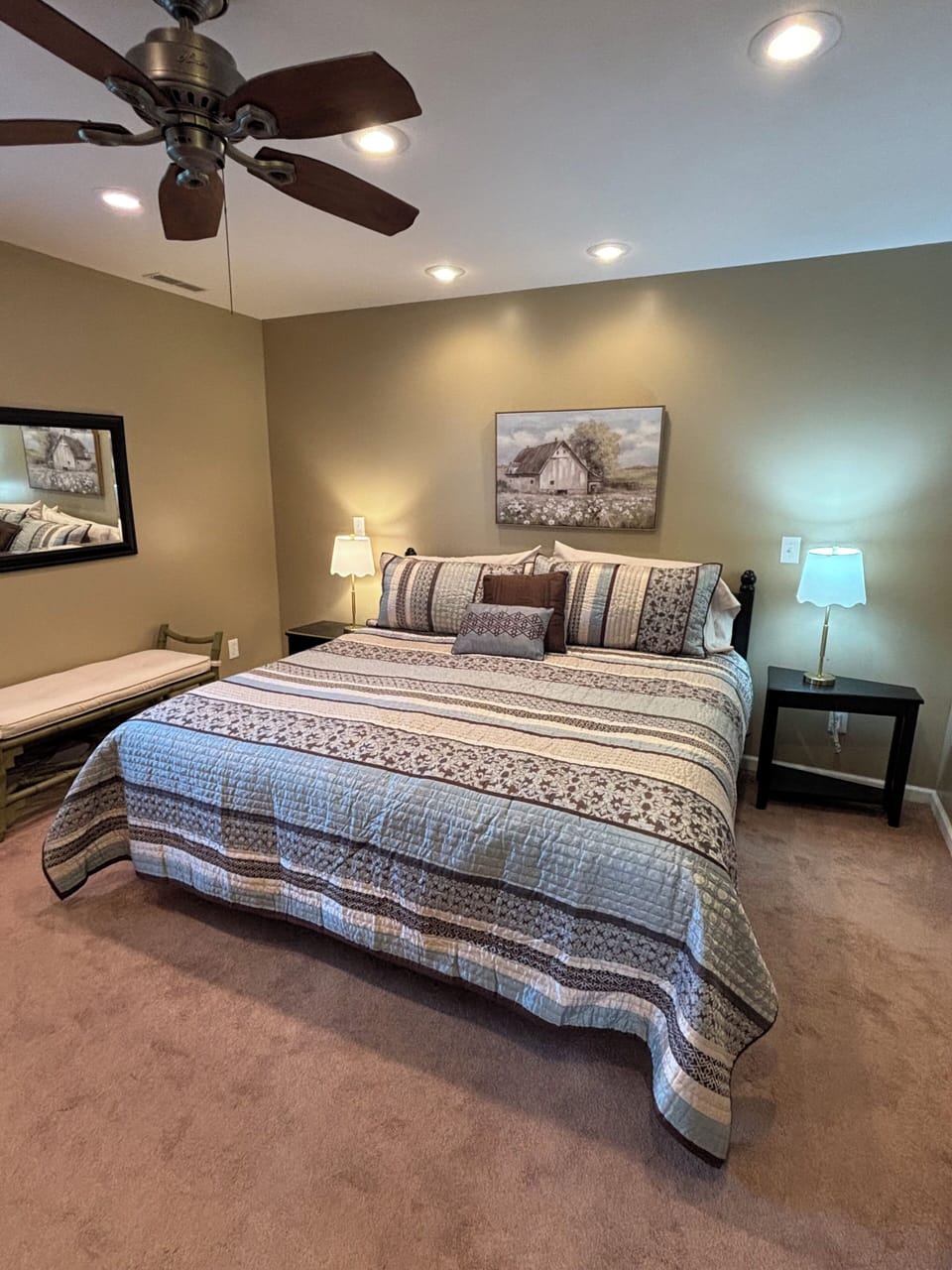 Cozy king suite with ceiling fan, soft lighting, and plush carpet