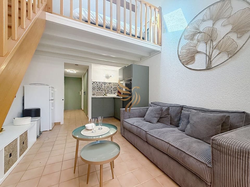 Salon cosy avec canapé confortable et cuisine équipée ouverte