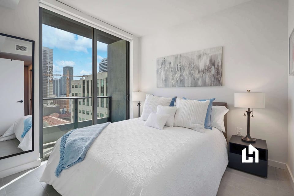 Peaceful bedroom with soft linens and large windows letting in plenty of natural light.