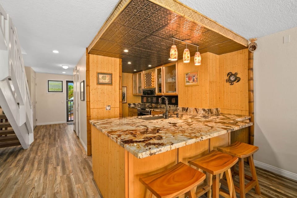 Open kitchen with granite island, bar seating, and warm bamboo finishes throughout