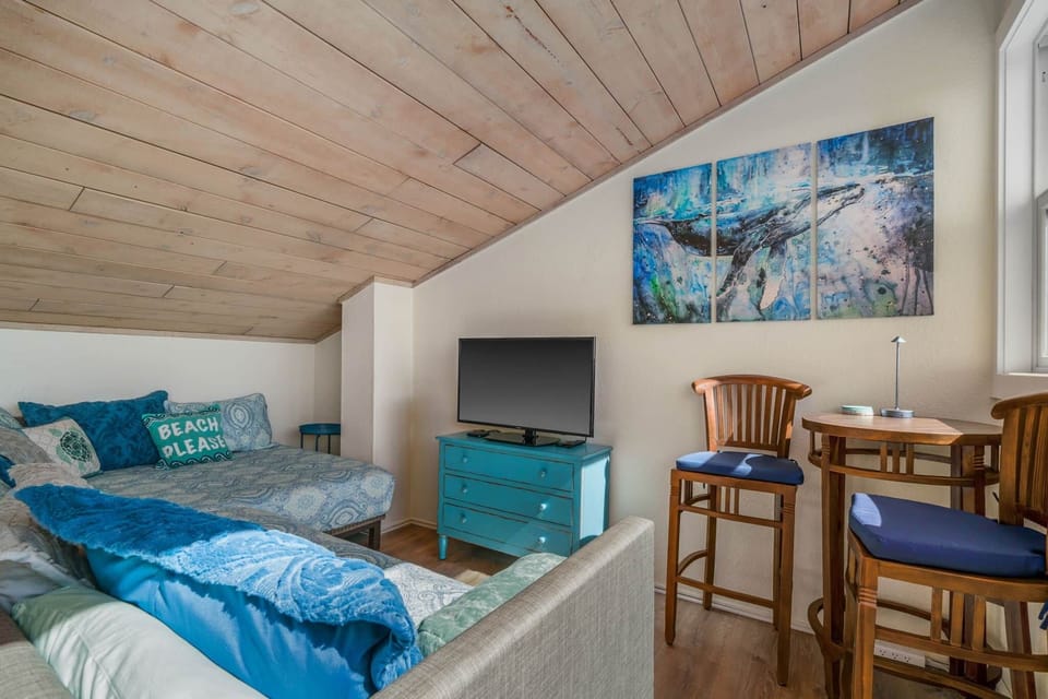 Relaxed loft space with daybed, TV, and natural light from the ocean-facing window