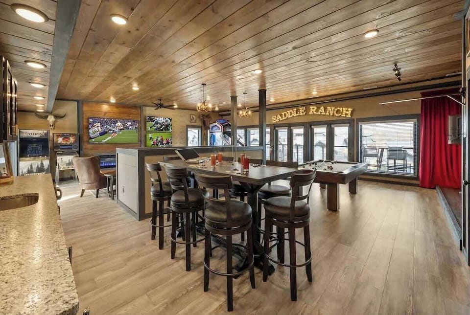 Open-concept gathering space w/ dining tables, TVs & rustic wood accents