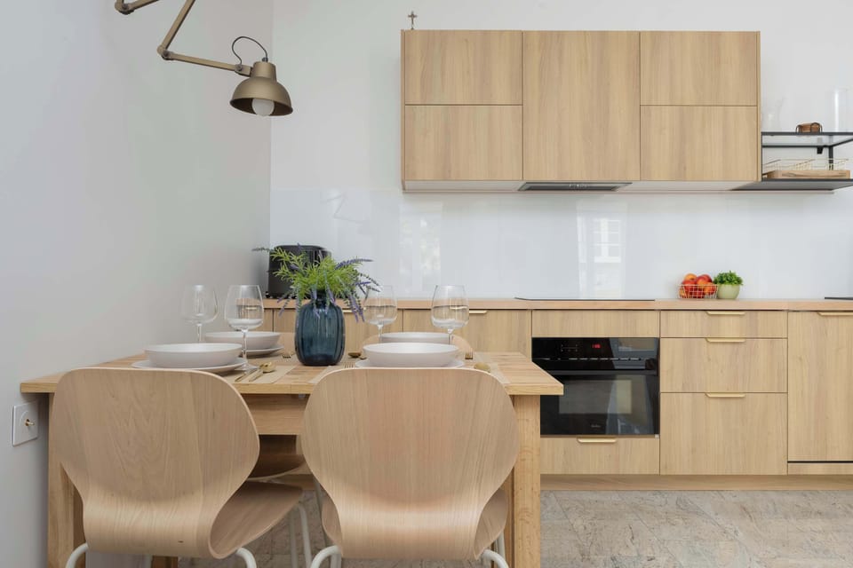 A view of the dining table, positioned right next to the kitchenette. Elegant spot lighting hangs above the table.