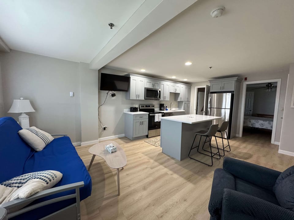 Open living room/kitchen space that includes a full futon and TV, picture is likeness only.