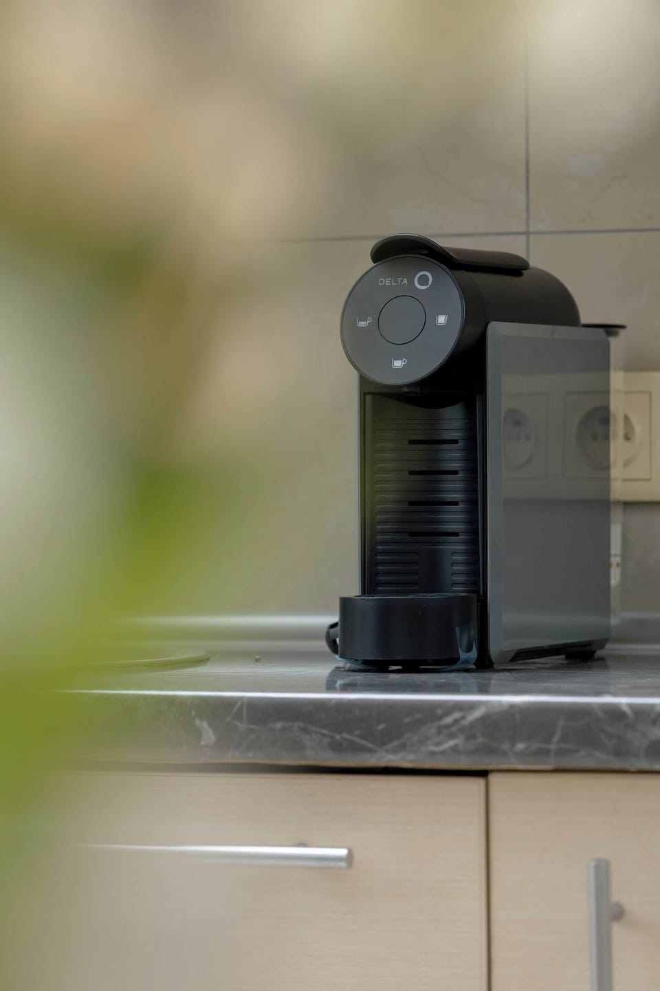 A focused shot on the kitchen counter shows a sleek black espresso machine, ready for a morning coffee. The blurred background emphasizes the quality of the provided amenities.