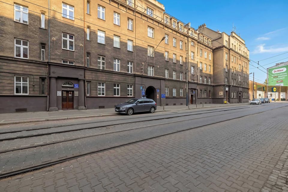The main street view shows the impressive scale of the building along a road with tram tracks. The surrounding architecture is consistent, featuring large windows and a sense of historical grandeur.