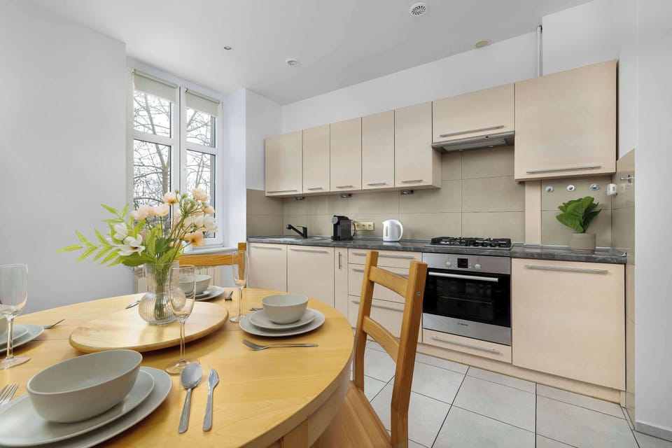 A bright kitchen with long rows of light-toned cabinetry and a dark countertop providing ample workspace. Built-in appliances like the oven and gas hob suggest a well-equipped culinary space.