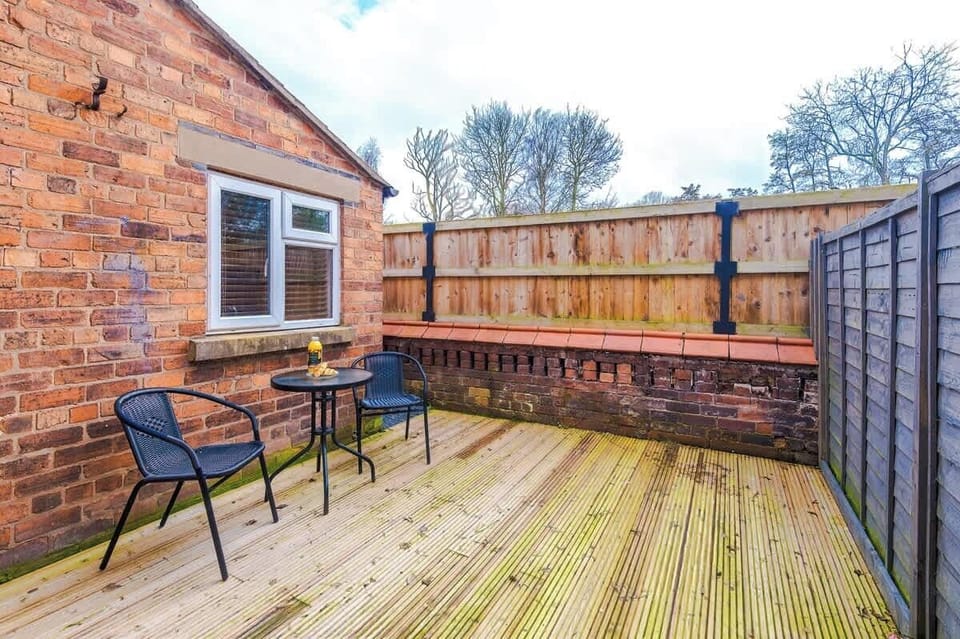 A small backyard with a table and two chairs, offering a peaceful outdoor space. There is open back space with fresh air, perfect for relaxing or enjoying a quiet moment outside
