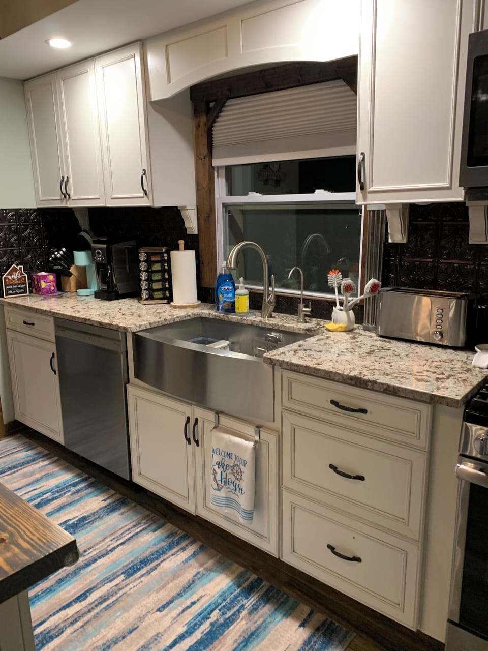 Kitchen stove/oven, microwave, sink, DW, knife rack, spices, & pots/pans.