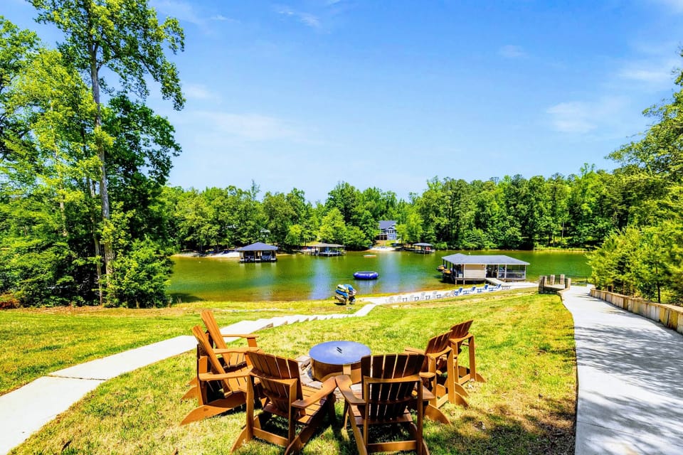 Lakefront - A circle of Adirondack chairs sits high on the lawn, overlooking the beach, boathouse, and water trampoline below.