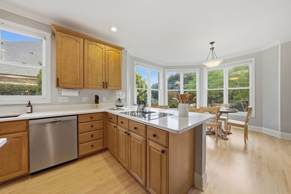 Bright modern kitchen with warm wood cabinetry and sleek stainless‑steel appliances.