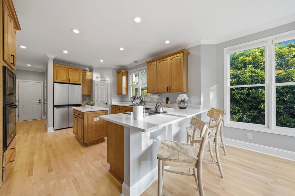 Bright modern kitchen with warm wood cabinetry and sleek stainless‑steel appliances.