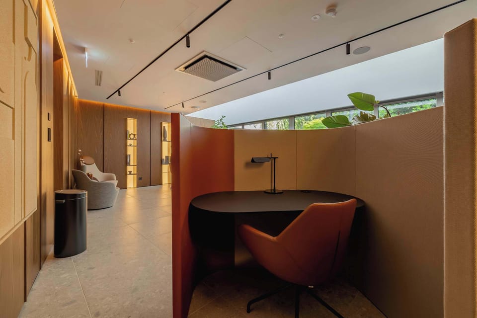 A cozy seating nook with soft chairs and a small table, partially separated for privacy. Subtle lighting and neutral tones create an intimate and शांत atmosphere. The design encourages quiet relaxation or conversation.