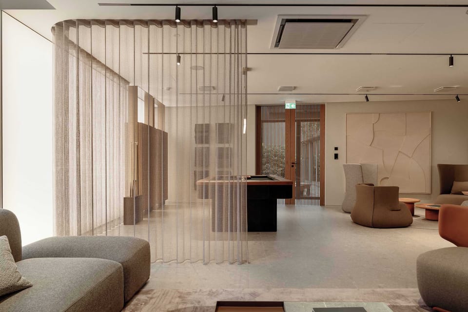 An open-concept lounge separated by sheer, floor-to-ceiling hanging curtains. The room includes comfortable low-profile seating and a billiards table visible in the background.