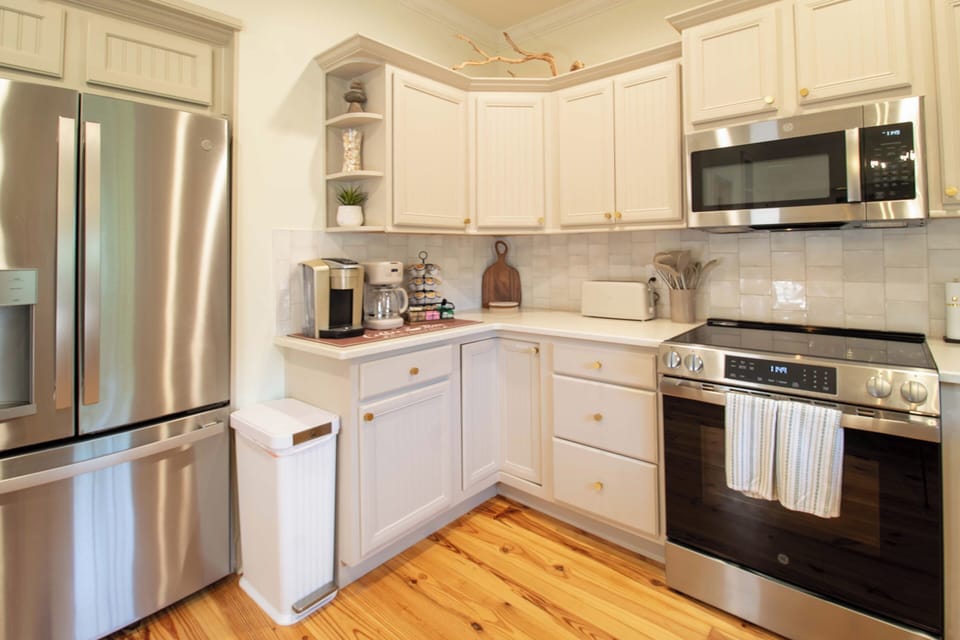 Cook your favorite meals in this bright, well-equipped kitchen featuring stainless steel appliances and warm wood floors.