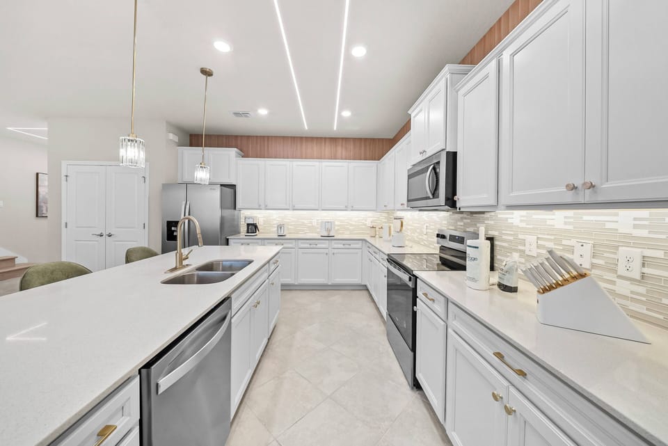 Experience a culinary haven with sleek white cabinetry and stainless steel appliances. The spacious, well-lit layout, complemented by a stylish backsplash, sets the perfect scene for your cooking adventures.