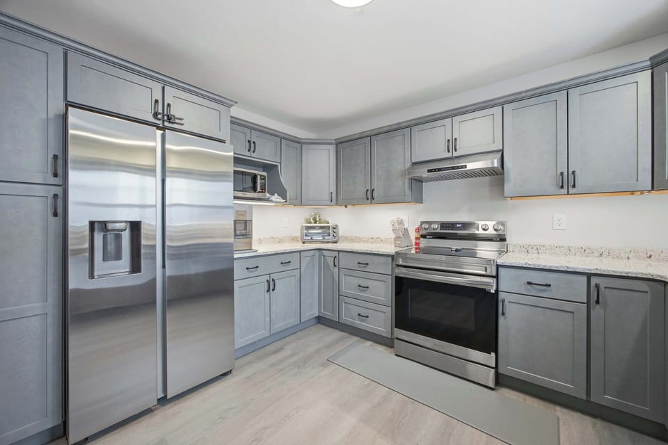 Another angle of the kitchen showing the full-size refrigerator, electric range, and generous counter space.