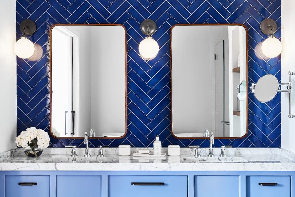 Refresh at the striking double vanity under warm, glowing sconces.