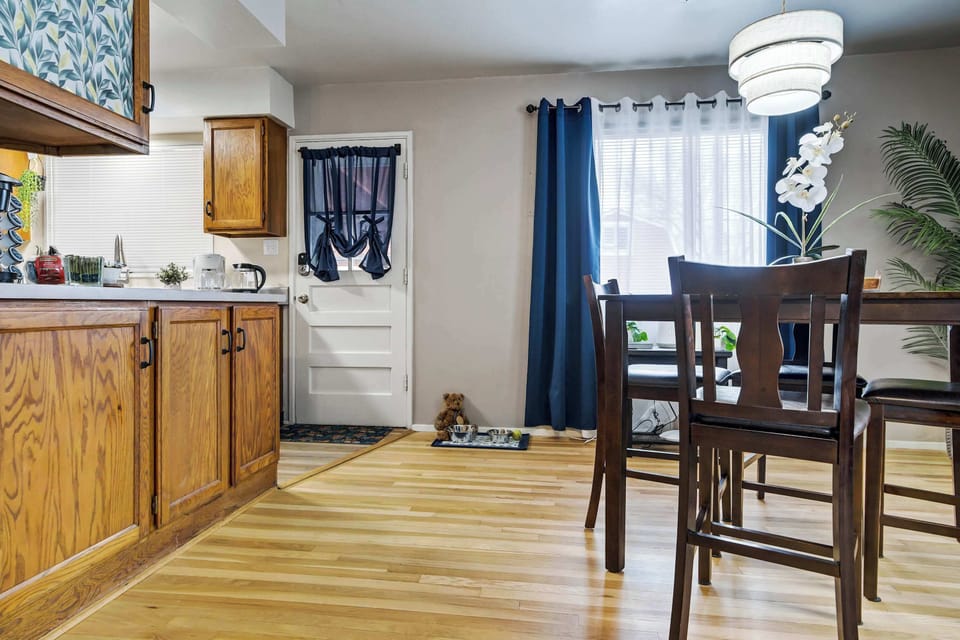 The L-shaped kitchen opens directly off the dining area, with warm oak cabinetry and light wood flooring carrying the home's consistent tone through the workspace. A window above the sink brings in natural light and keeps the space feeling open.