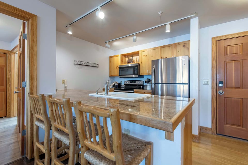 Fully equipped kitchen with granite counters, stainless steel appliances, and bar seating