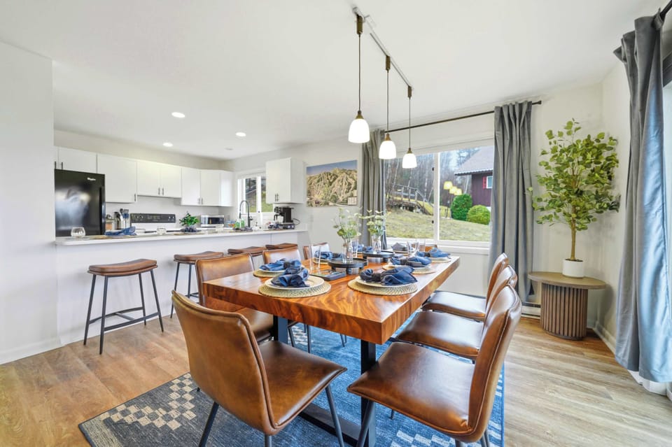 The kitchen and dining area from above — the island, the walnut table, and the mountain light all in one frame.