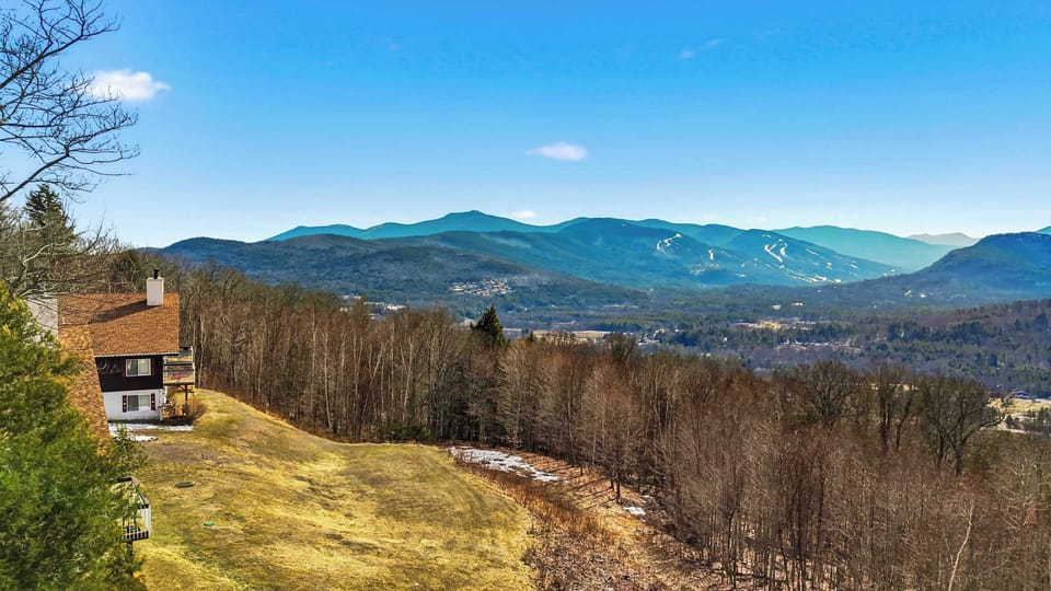 The view from the property looking down into the valley, with the mountains and a neighboring rooftop visible below.