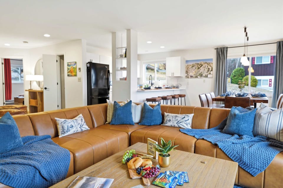 The sectional has room for everyone — deep cushions, blue throw pillows, and the kind of couch that makes leaving feel optional.