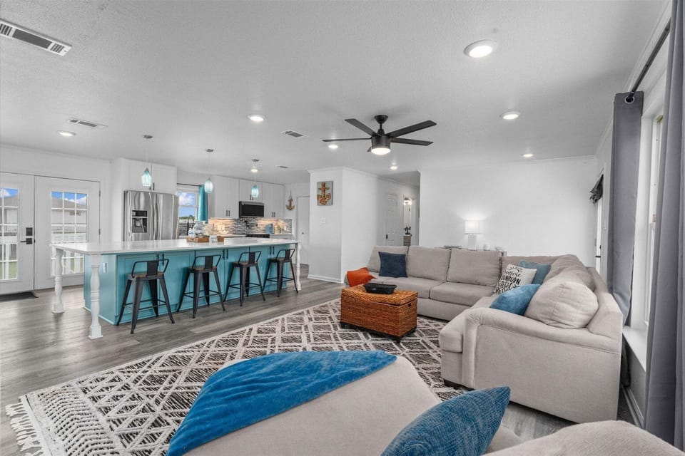 Open living space with sectional couch, ceiling fan, and seamless flow into kitchen.