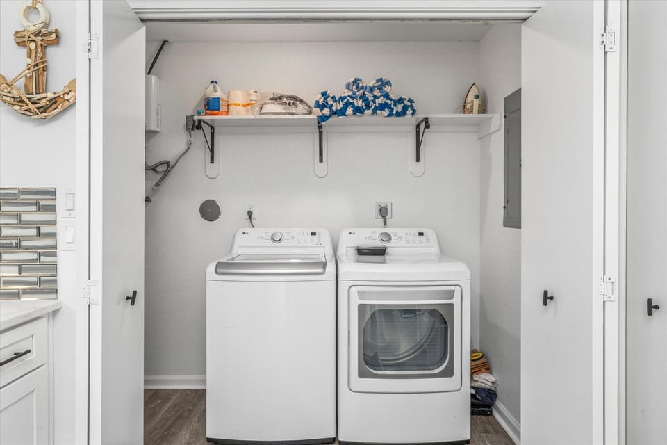 Laundry room with washer and dryer, shelving, and functional workspace.