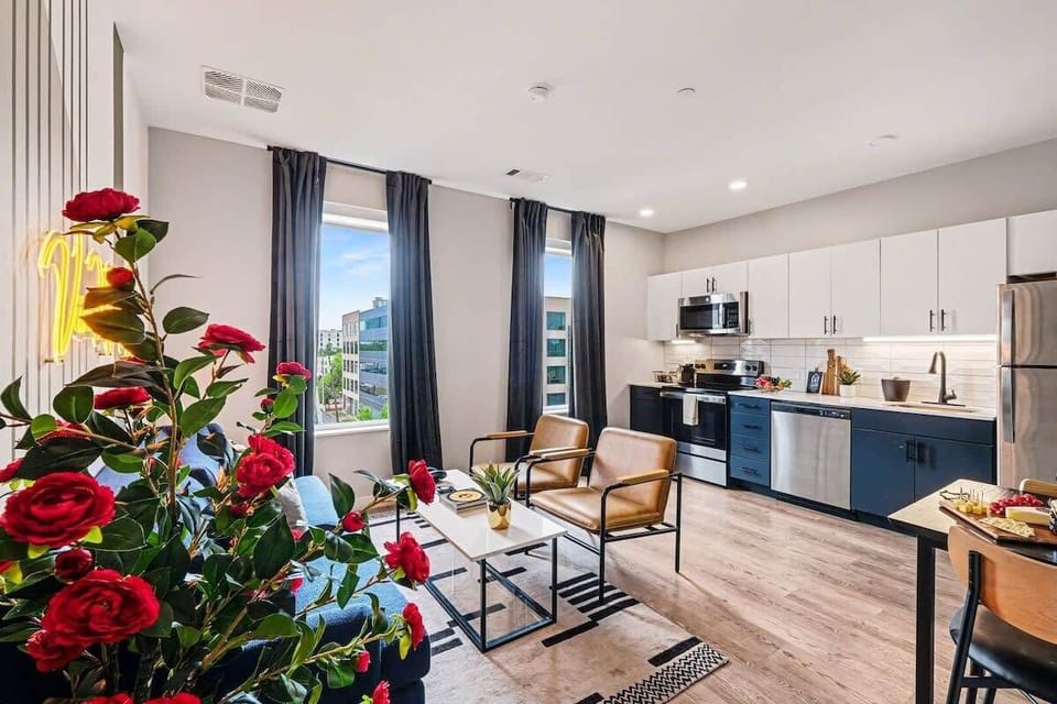 Bright and open living area featuring a smart TV and plush furnishings. Connects to the dining area and kitchen.