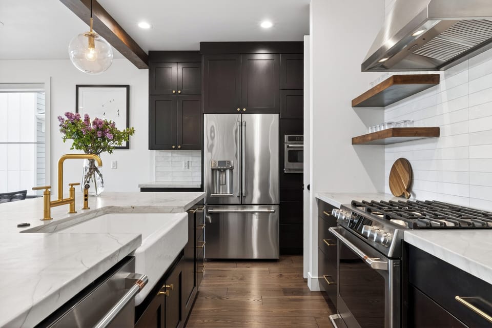Modern kitchen with marble countertops, brass accents, and warm wood shelving for a polished, inviting feel.