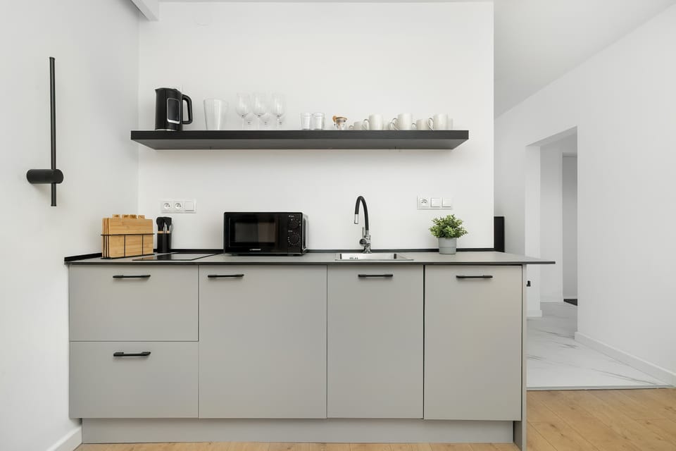 A modern kitchen corner with clean lines and a neutral palette. Subtle decorative elements on the shelves add character without cluttering the space. The layout is practical, offering everything needed for everyday cooking.