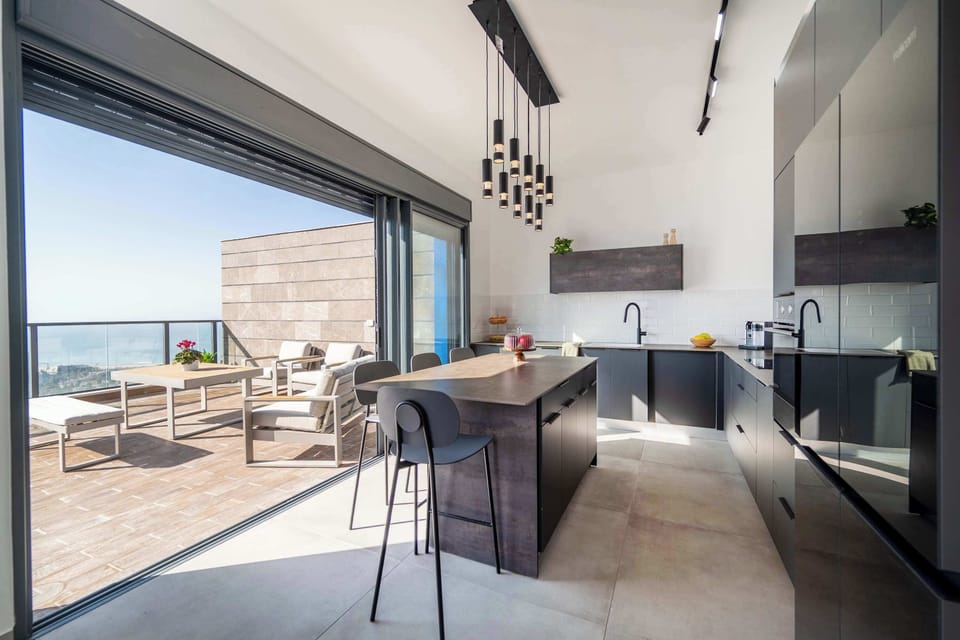 Indoor-outdoor kitchen connection invites morning coffee beside skyline breezes.