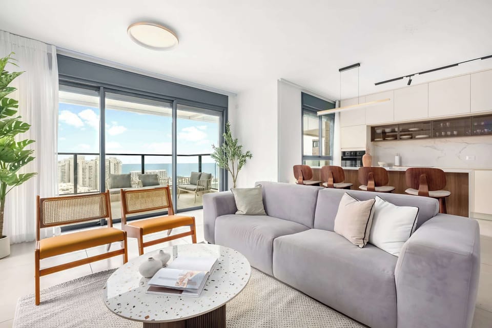 Sunlit lounge with plush sofa, sculptural table, skyline balcony, seamless flow into stylish cooking zone
