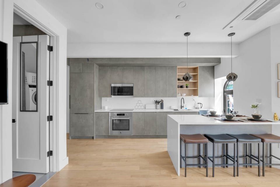 Sleek, handleless grey cabinetry and a waterfall-edge kitchen island in a modern space.