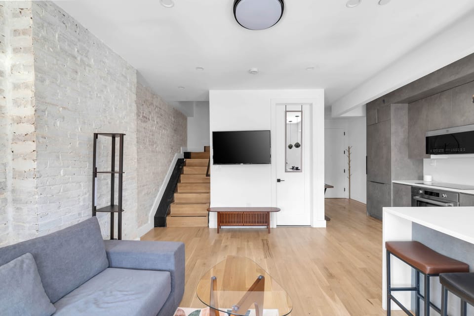 Contemporary living space with an exposed white-brick wall and a wall-mounted TV